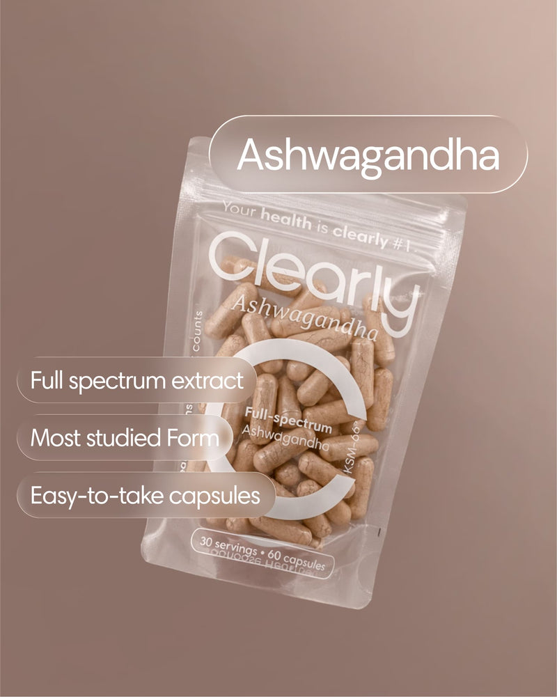 Close-up of Clearly Ashwagandha capsules in a clear container, showing small, brown herbal supplement capsules on a white background.